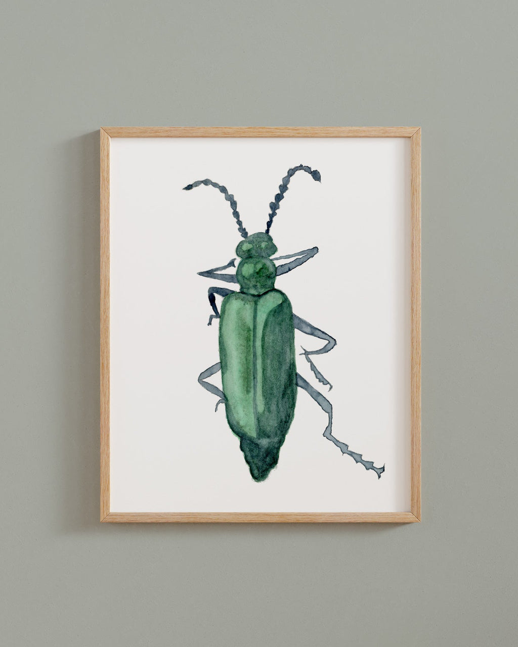 Framed watercolor painting of a green beetle on a white background